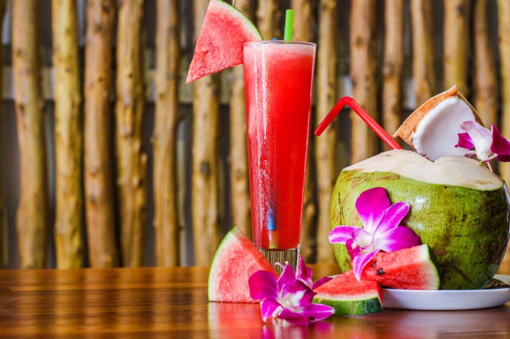 A watermelon juice and a fresh coconut on a café table