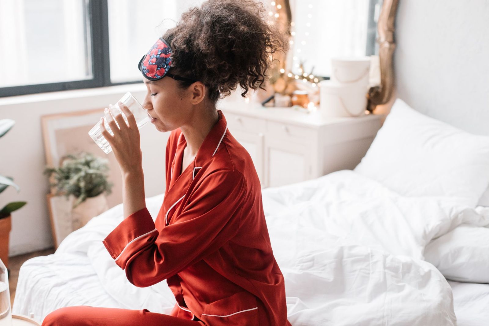 A woman sitting in bed drinking a glass of water in the morning