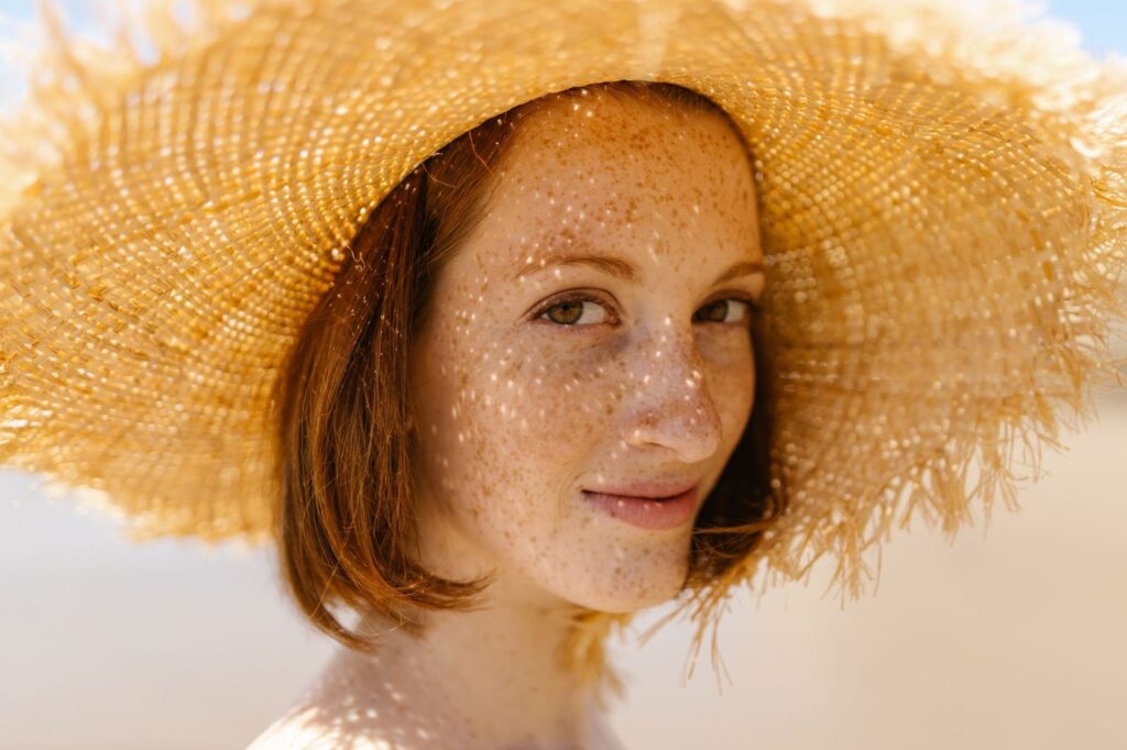 A freckled woman in a straw sun hat