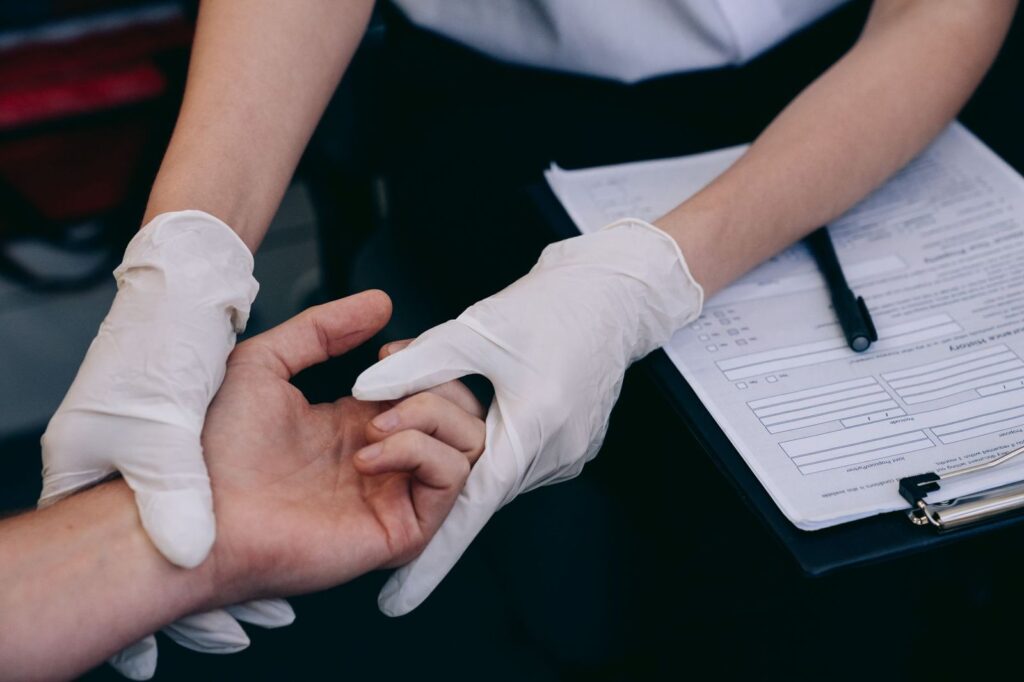 Gloved hands checking a patient's wrist