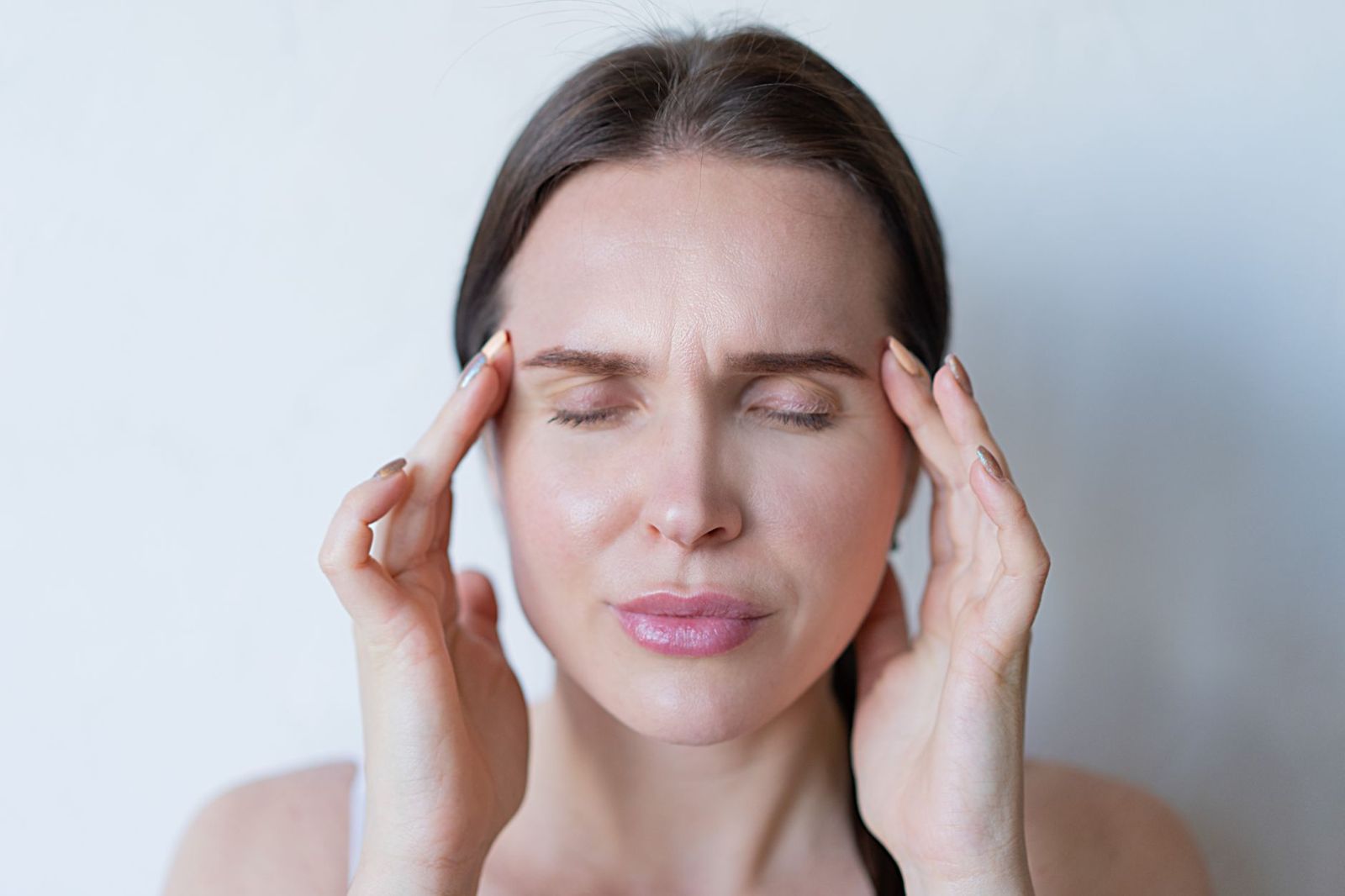 A woman pressing her temples with a headache