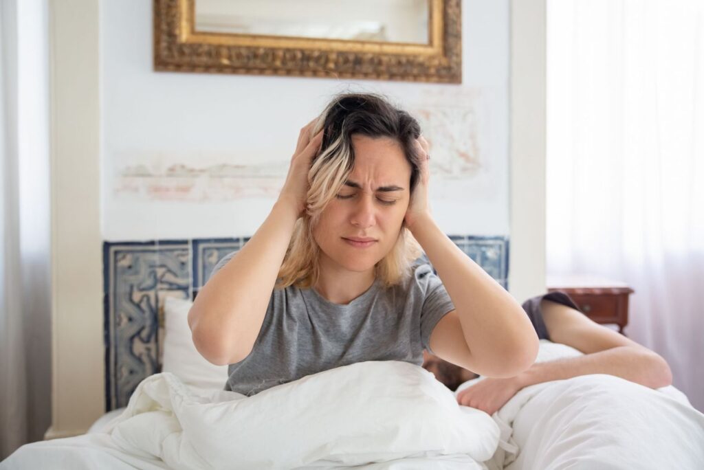 A woman sitting in bed holding her head