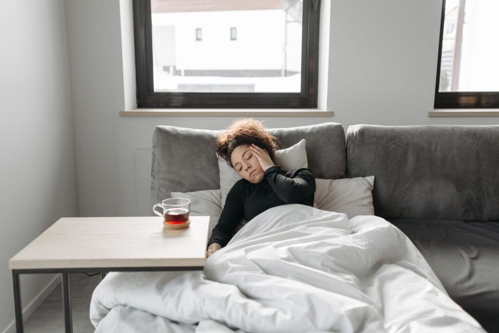 A tired woman sitting up in bed under a duvet