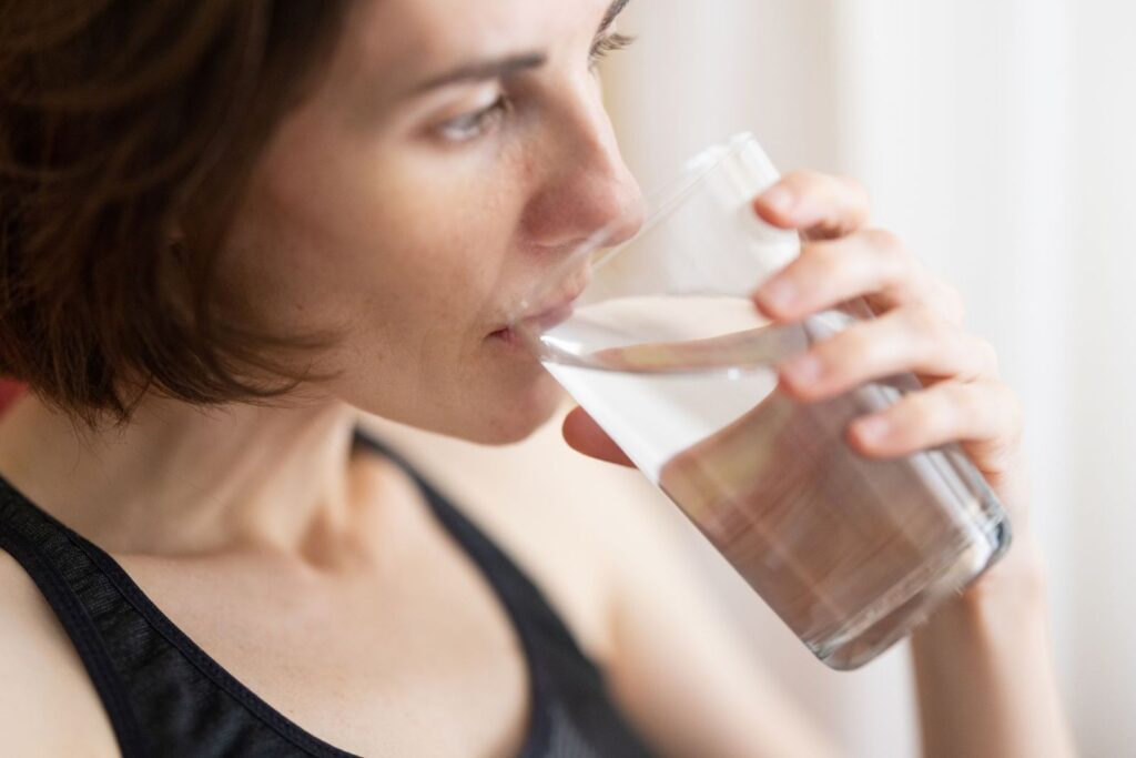 A woman taking small sips from a glass of water
