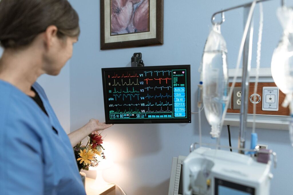 A nurse checking a monitor beside IV drip bags