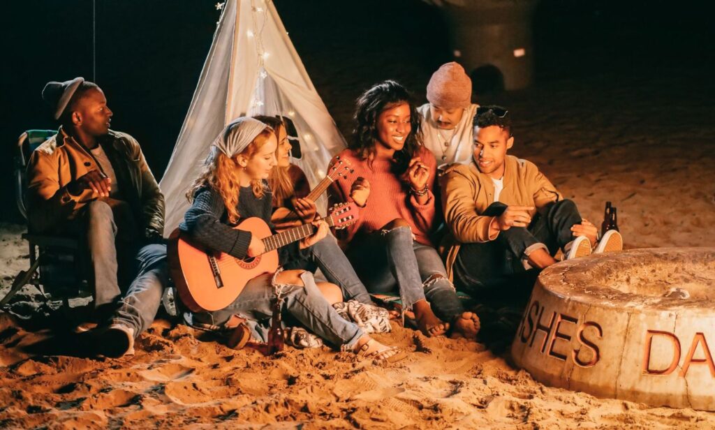 Friends around a bonfire on the beach at night