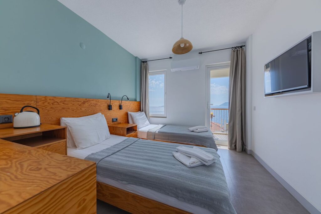 A bright, simple hotel room with a balcony