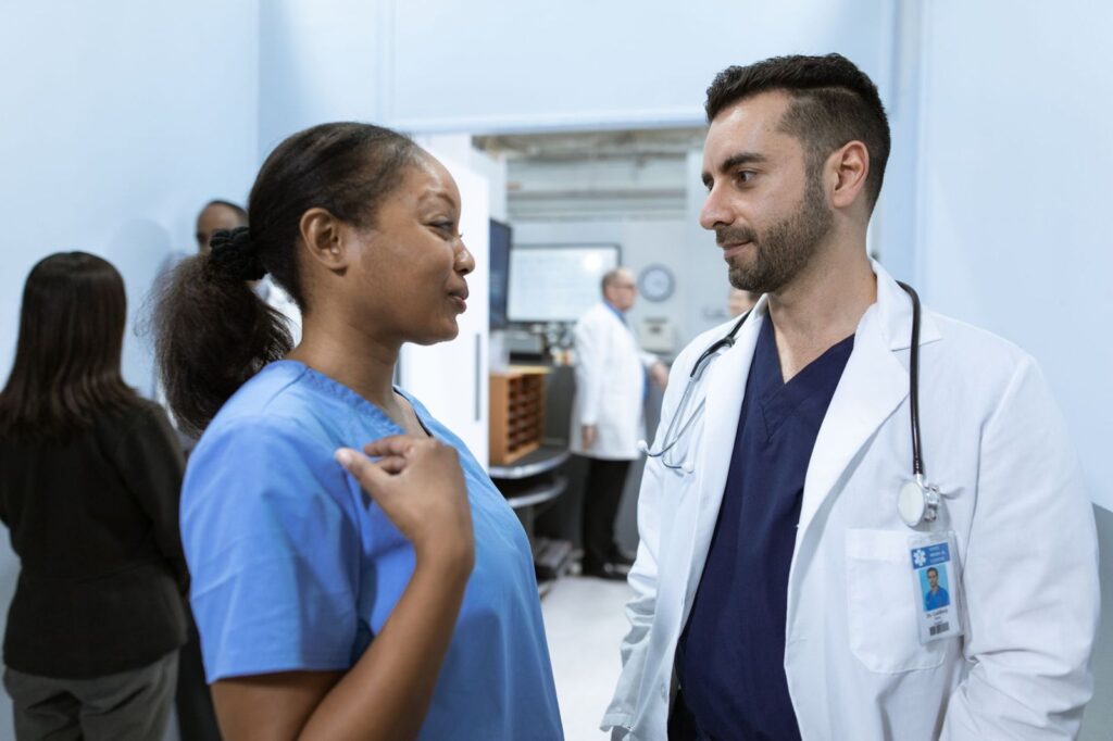A nurse and a doctor talking in a clinic corridor