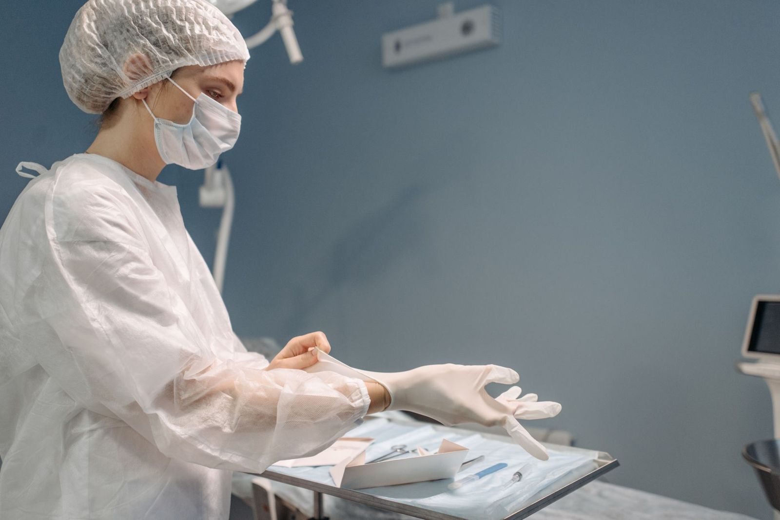 A healthcare worker in gloves and mask preparing a sterile tray