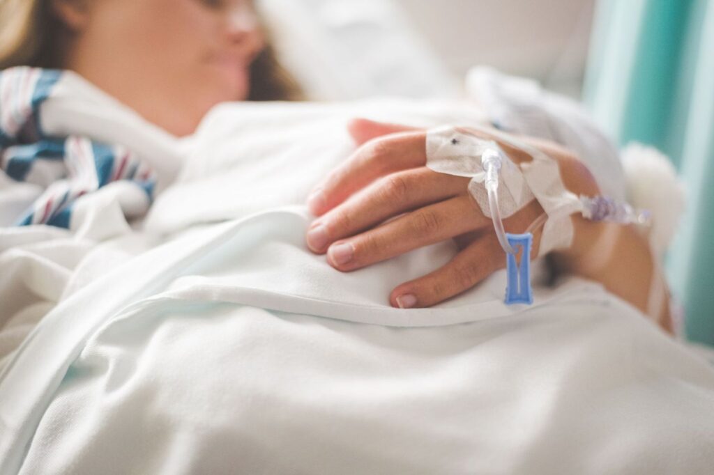A patient resting with an IV cannula taped to the hand