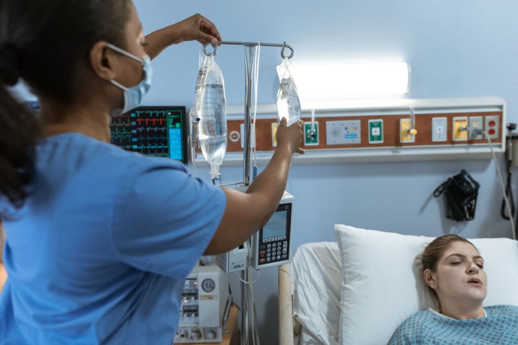 A nurse adjusting an IV drip for a resting patient