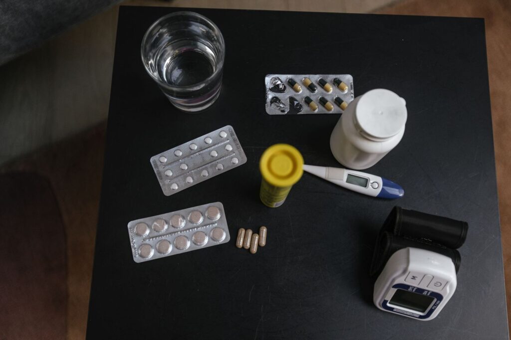 Medicines, a thermometer and a glass of water on a table