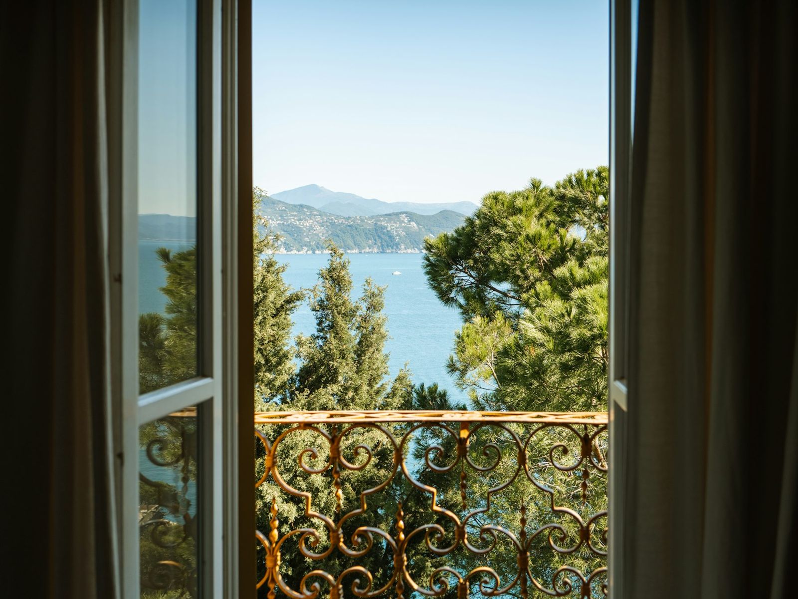 An open window looking out over trees to the sea