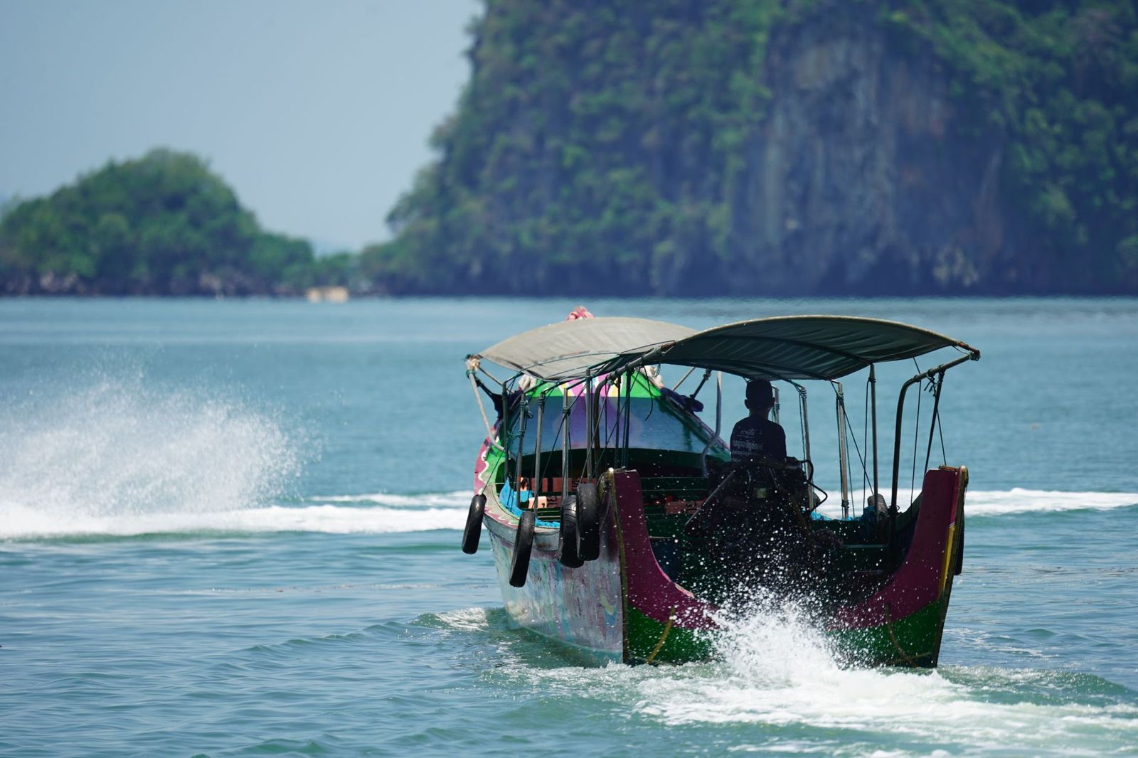 A longtail boat speeding past limestone islands