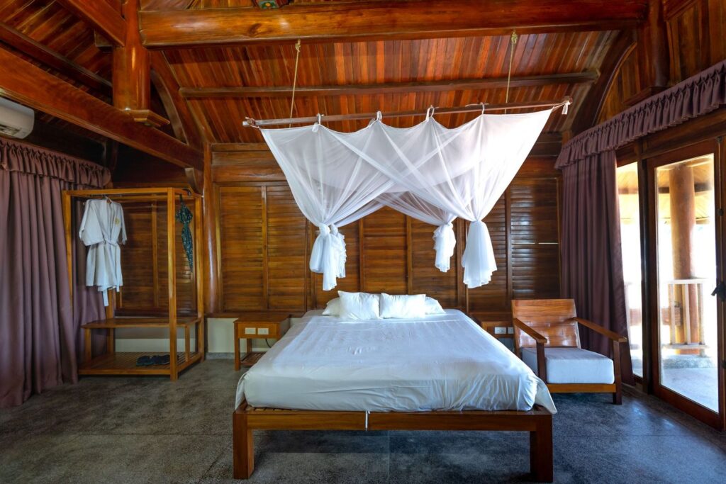 A quiet wooden hotel bedroom with a canopy bed