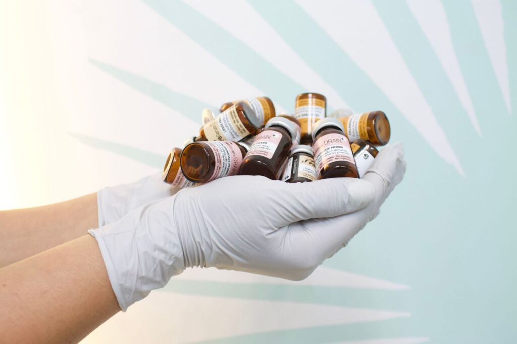 Gloved hands holding small medicine vials