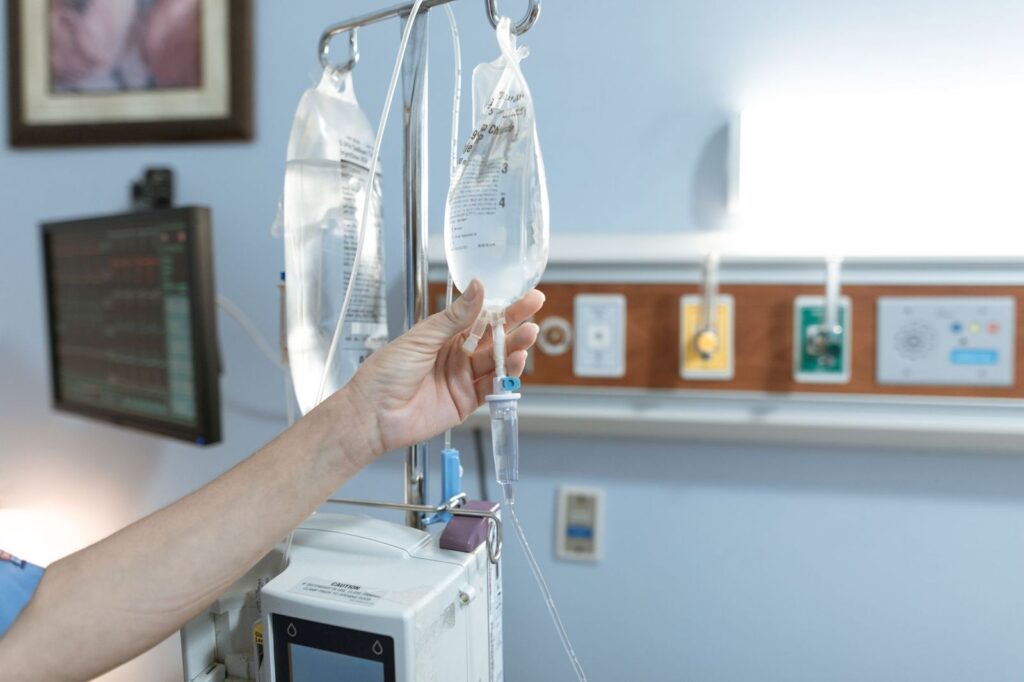 A nurse adjusting an IV drip bag on its stand