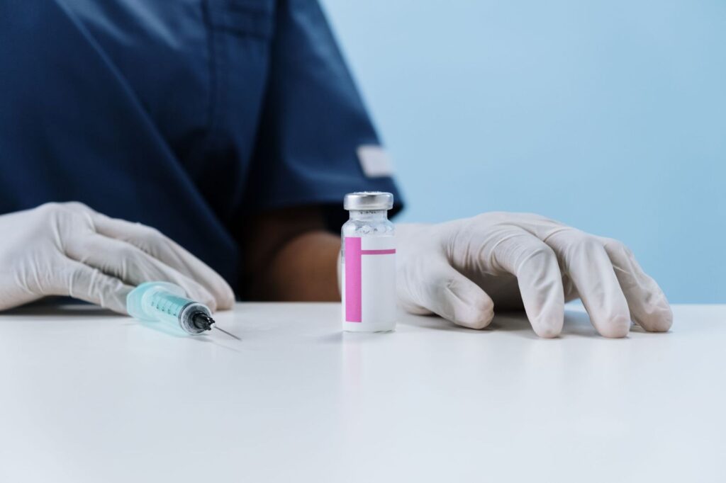 Gloved hands with a syringe and a medicine vial