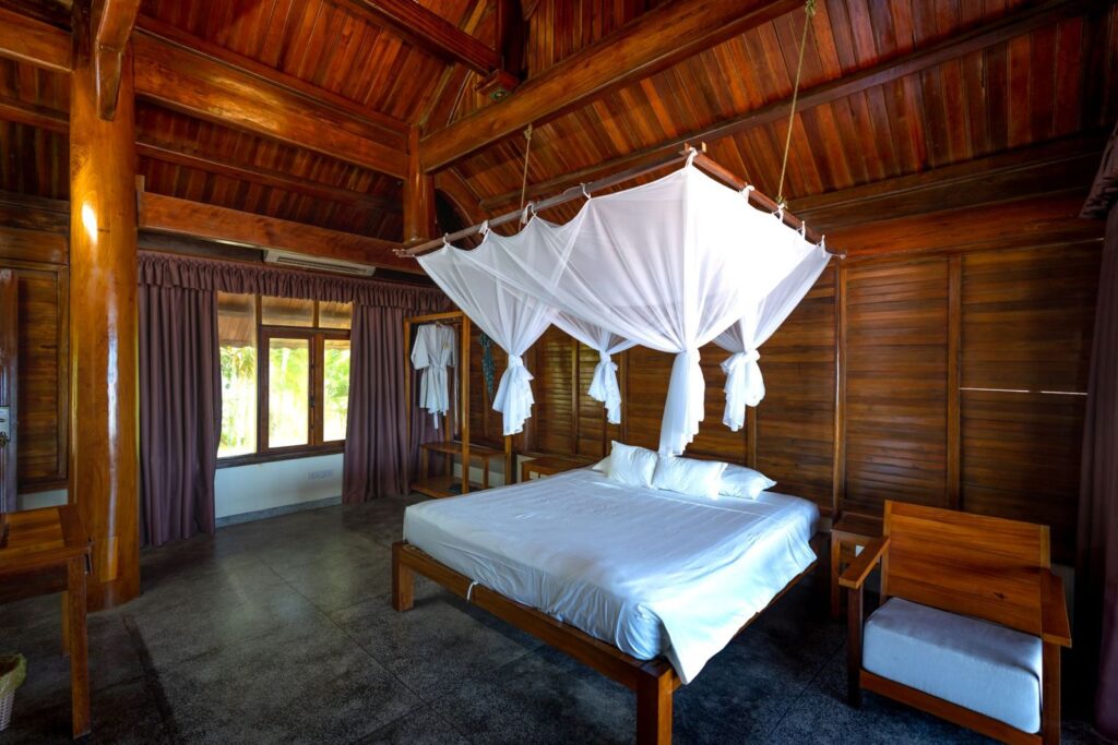 A calm wooden bedroom with a white canopy bed