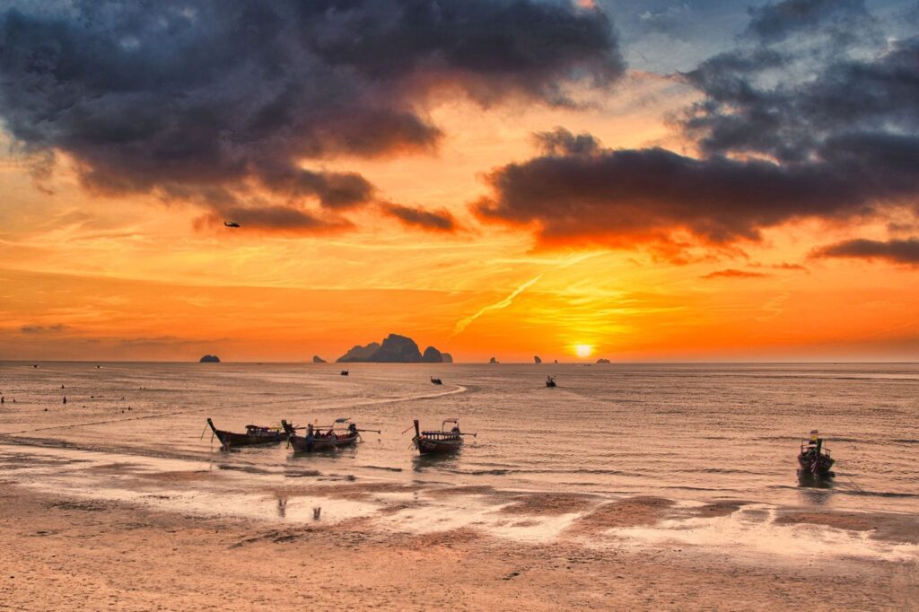 Sunset over a Krabi beach with longtail boats