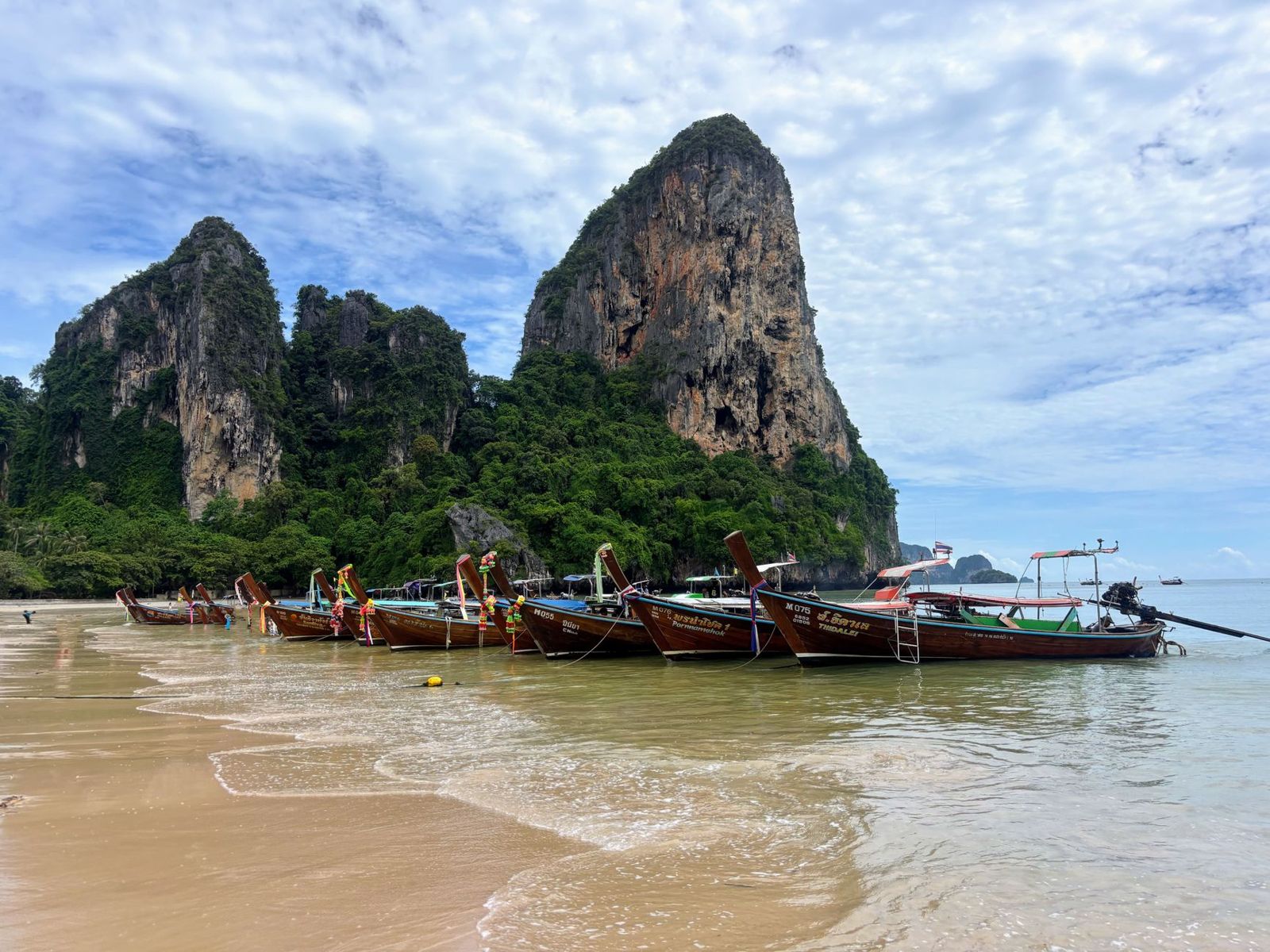 Longtail boats on Railay Beach in Krabi below limestone cliffs
