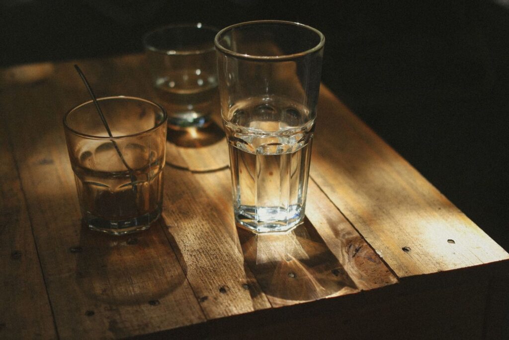 Glasses of water on a sunlit wooden table