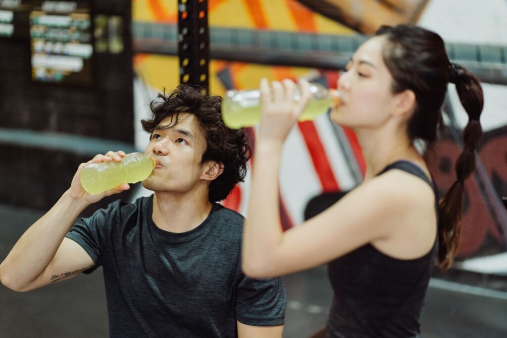 Two people drinking from bottles after exercise