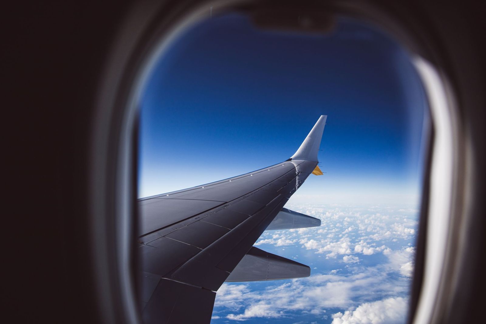 An aircraft wing above the clouds seen from a cabin window