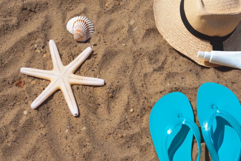 A sun hat, flip-flops and a starfish on the sand