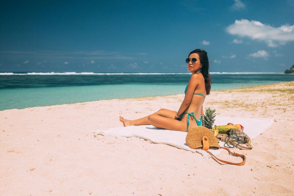 A woman sitting on a beach in the sun