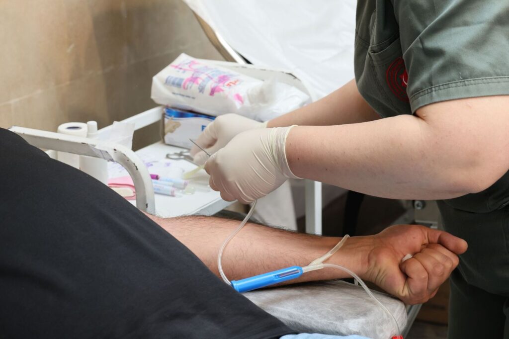 A nurse in gloves placing an IV cannula in a patient's arm